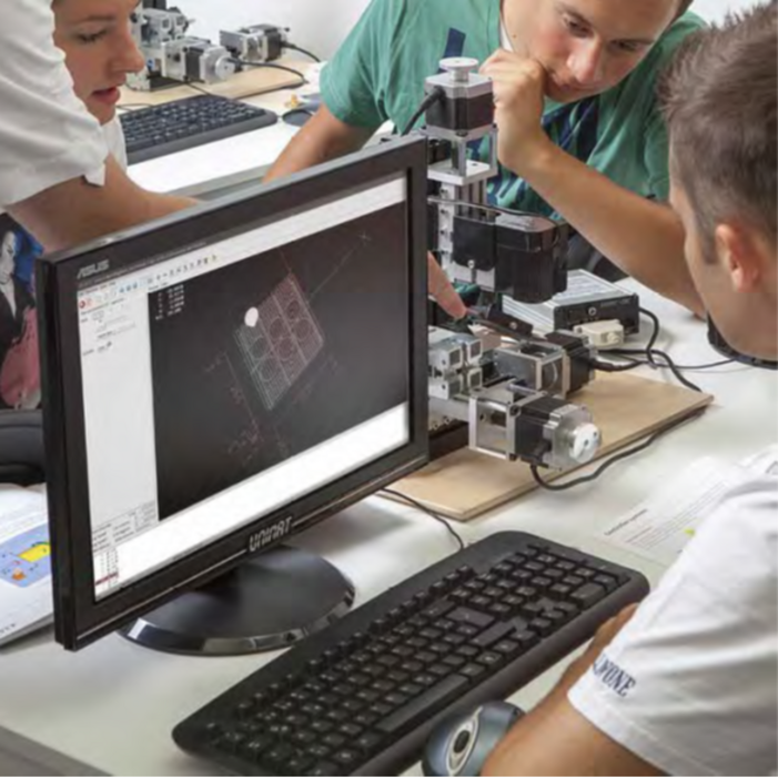 CNC Makerspace mit Computer und 4 Achsenfräse auf einem Werktisch mit Schülern