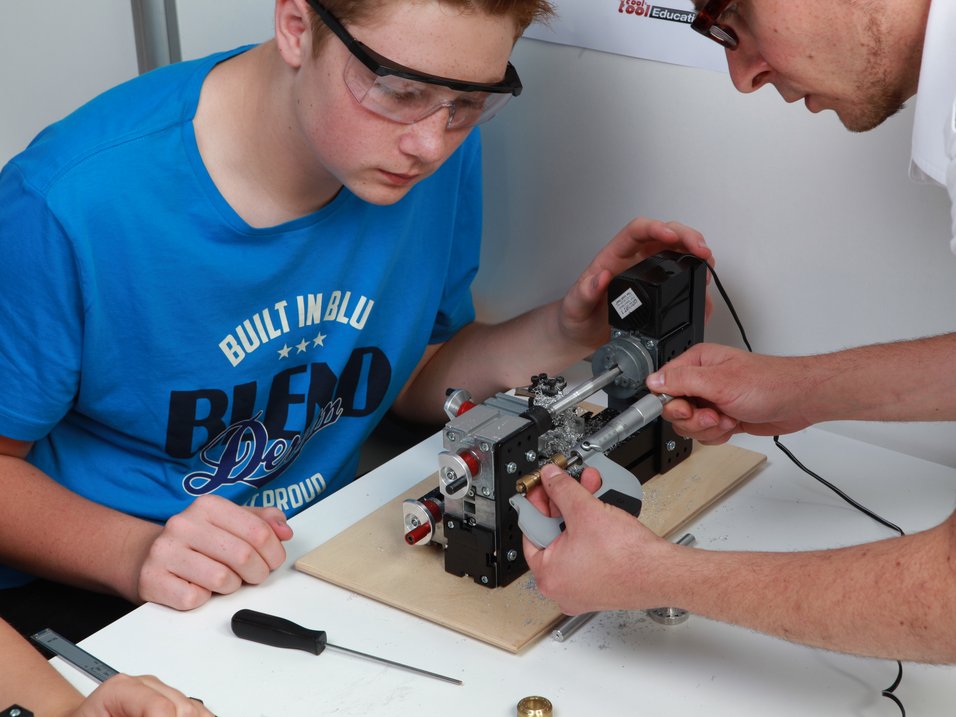 UNIMAT Technikset im Unterricht, Lehrer misst mit Schüler gemeinsam ein Werkstück